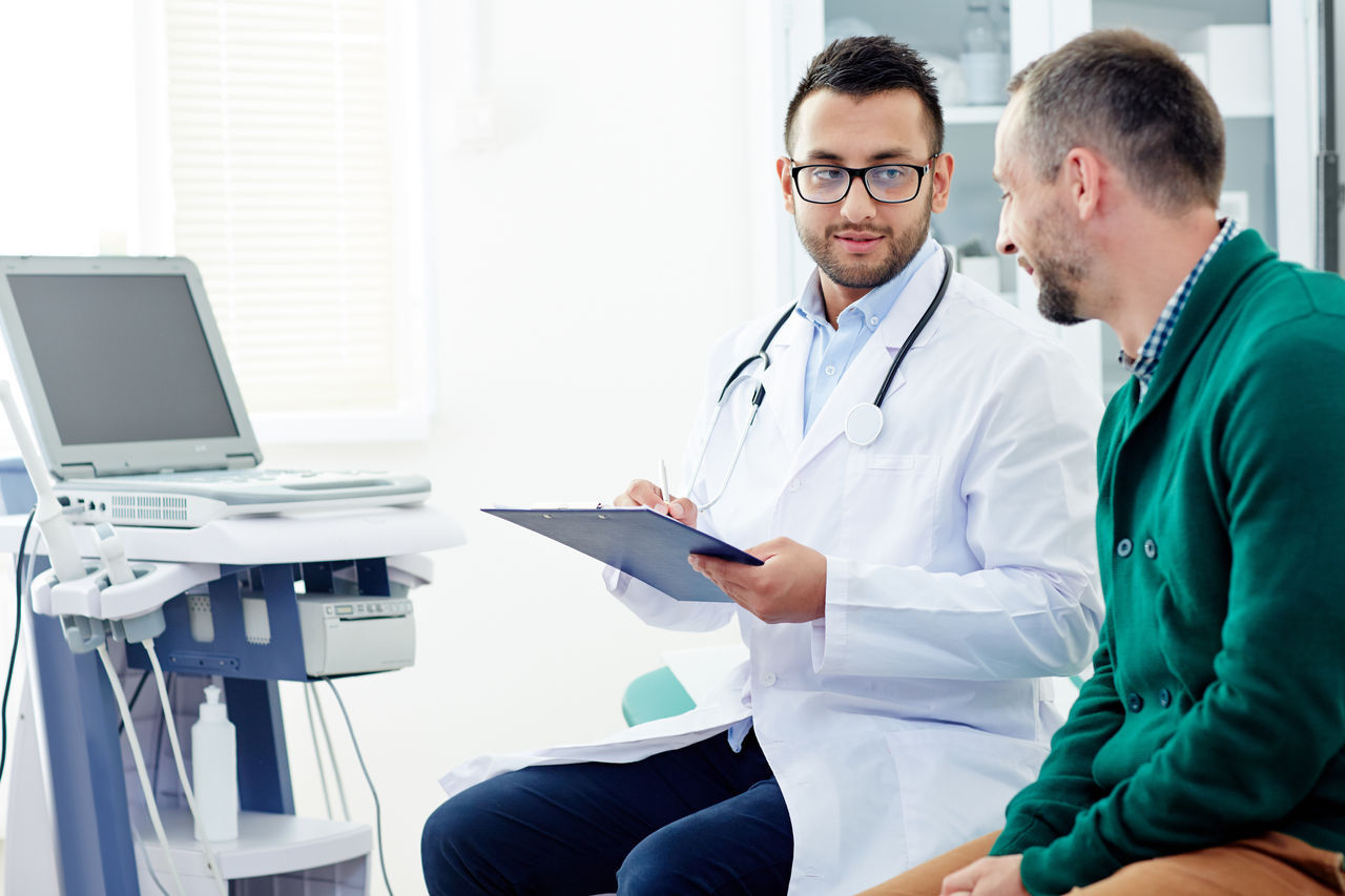 Doctor with clipboard consulting one of patients and making prescriptions